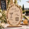 Natural wood personalized signature drinks wedding sign displayed at an outdoor wedding bar