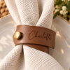 Charlotte Leather Napkin Ring Brown faux leather napkin ring engraved with Charlotte and finished with a gold button on a white wedding napkin